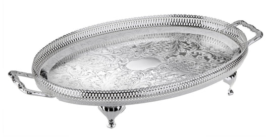 An oval-shaped silver-plated metal tray with handles and legs, featuring intricate designs on the surface.